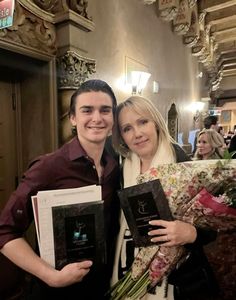 a man and woman standing next to each other holding flowers in their hands while smiling at the camera