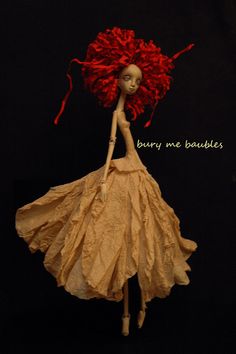 a doll with red hair is wearing a yellow dress and holding a large red flower