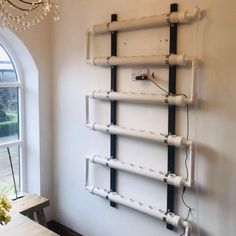 a white wall with pipes on it and a chandelier hanging from the ceiling