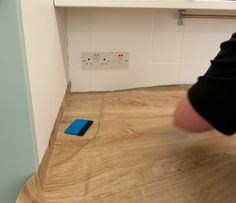 a person standing in front of a counter with a blue object on the floor next to it