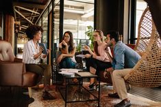 group of people sitting around a coffee table in an office setting with wicker chairs