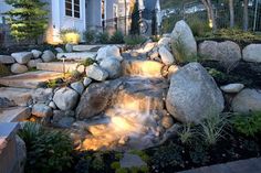 rock landscaping ideas with water flowing from the rocks and lighting up the area around it