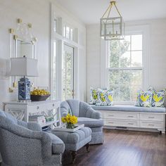 a living room filled with furniture and yellow flowers in vases on the window sill