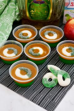 small cups filled with desserts sitting on top of a table next to an apple