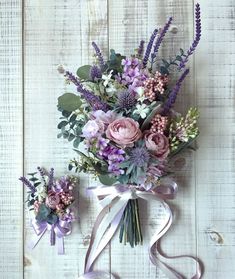 a bouquet of flowers sitting on top of a white wooden table next to another bouquet