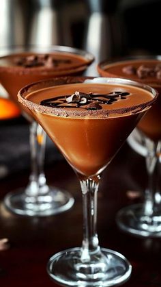 three glasses filled with chocolate martinis sitting on top of a table