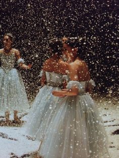 two women standing in the snow wearing dresses