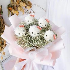 a bouquet of white flowers with little black cats on them and baby's breath