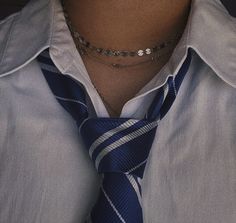 a man wearing a black and white striped tie with a silver bead necklace on his neck