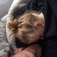 a man and woman laying in bed with their heads together, one is sleeping on the other side