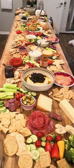 a long table covered with lots of different types of cheeses and crackers on it