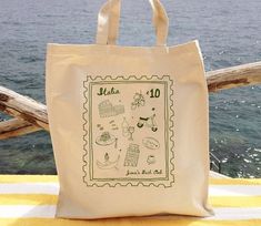 a tote bag sitting on top of a yellow table cloth next to the ocean