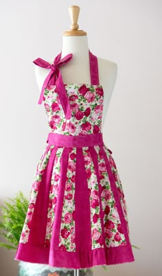 a dress on a mannequin with pink flowers and green plants in the background