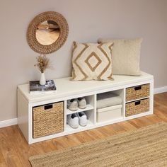 a white bench with baskets and shoes on it in front of a wall mounted mirror