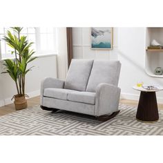 a living room with a gray chair and potted plant