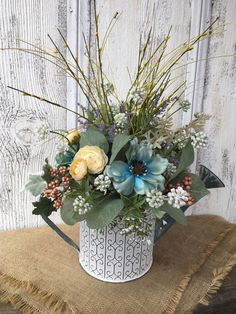 a white vase filled with lots of flowers on top of a burlap table