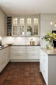 a kitchen with white cabinets and wood floors