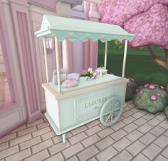 a small ice cream cart sitting in front of a pink flower covered tree and bushes