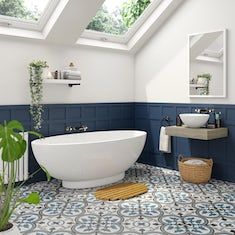 a white bath tub sitting under a bathroom window next to a sink and a mirror