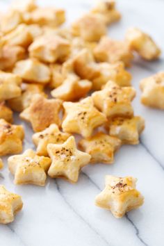 chopped up pieces of food sitting on top of a white marble countertop with black pepper sprinkles