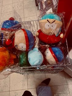 several stuffed animals sitting in a basket on the floor next to a person's feet