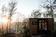 a small wooden cabin in the woods at sunset