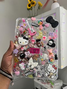 someone holding up a case with hello kitty stickers on it