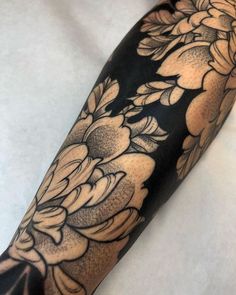 the arm is covered with black and white tattoos on it's arms, which are decorated with flowers