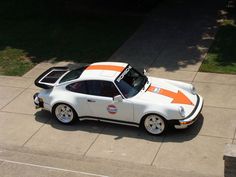 an orange and white car is parked on the sidewalk