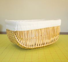 a wicker basket sitting on top of a yellow cutting board next to a wall