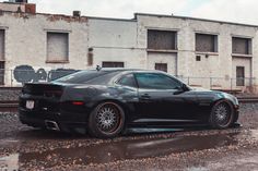 a black sports car parked in front of an abandoned building