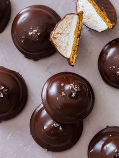 chocolate covered pastries with one cut in half and the other partially eaten, sitting on a white surface