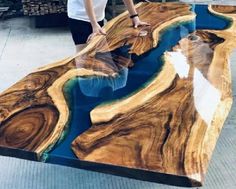 a person standing on top of a table made out of wood and blue glass in the middle