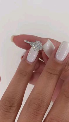 a woman's hand with white manies and a diamond ring on her finger