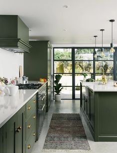 a kitchen with green cabinets and an area rug in front of the counter top that matches the floor