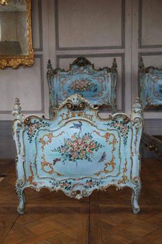 an antique bed with blue and gold paint on it