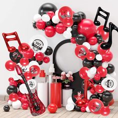 the balloon arch is decorated with black, white and red balloons that spell out musical instruments