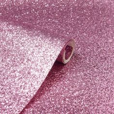 a roll of pink glitter paper on top of a purple table cloth with a white ring