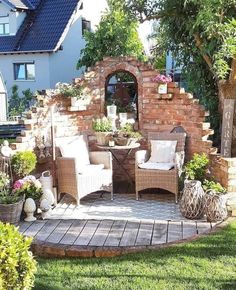 a patio with chairs, tables and potted plants on the ground in front of a brick wall