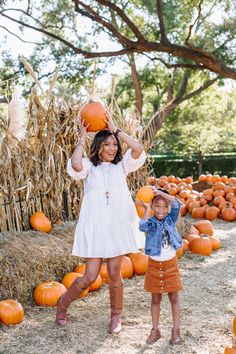 a woman and child holding pumpkins in their hands