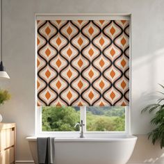 a bathroom window with an orange and black patterned roller shade over the bathtub in front of it