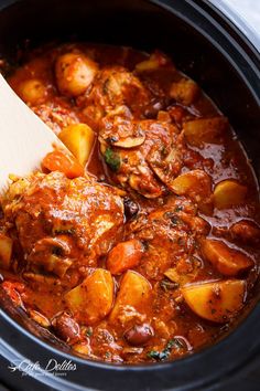 the crock pot is full of stew and potatoes with a wooden spoon in it