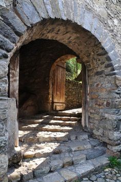 an old stone tunnel with steps leading into the door and light coming in from behind