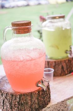 a pink liquid in a glass jug sitting on top of a tree stump