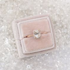 an engagement ring in a velvet box on top of glittery surface with sparkle around it