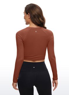 the back view of a woman wearing an orange crop top and black leggings