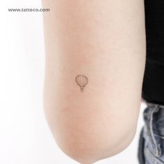 a small hot air balloon tattoo on the back of a woman's right arm