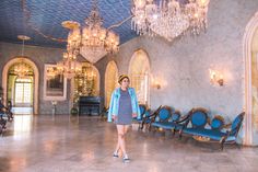 a woman standing in a room with chandeliers