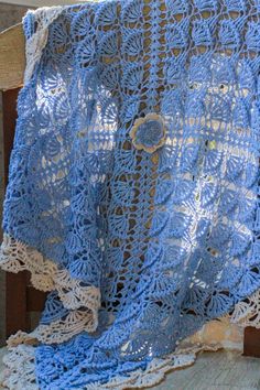 a blue crocheted blanket sitting on top of a wooden chair