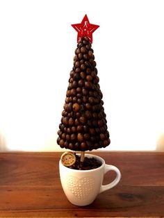 a small christmas tree made out of coffee beans in a mug with a corkscrew on top